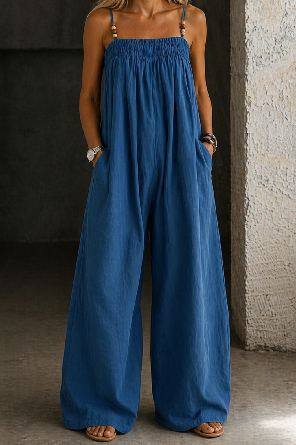 Combinaison en denim bleu ample à bretelles fines, taille froncée, jambes larges.