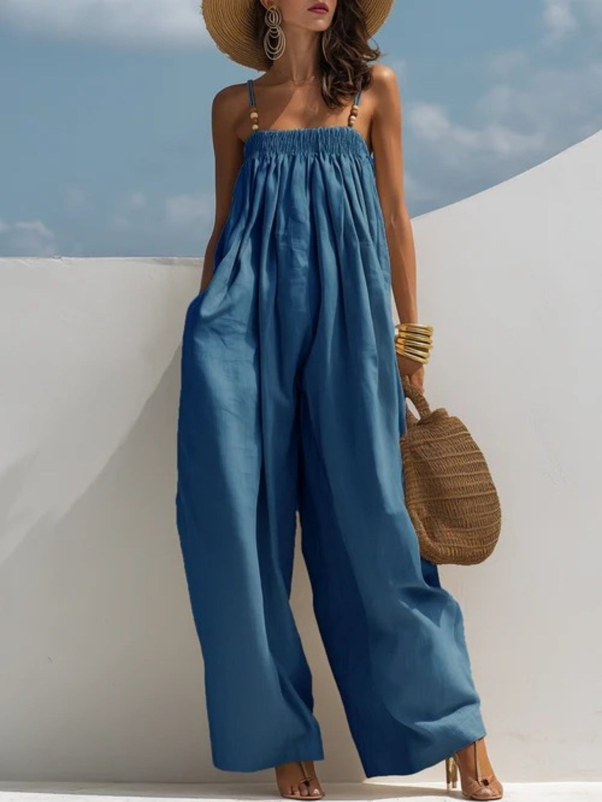 Combinaison en denim bleu ample à bretelles fines, taille élastiquée, jambes larges.