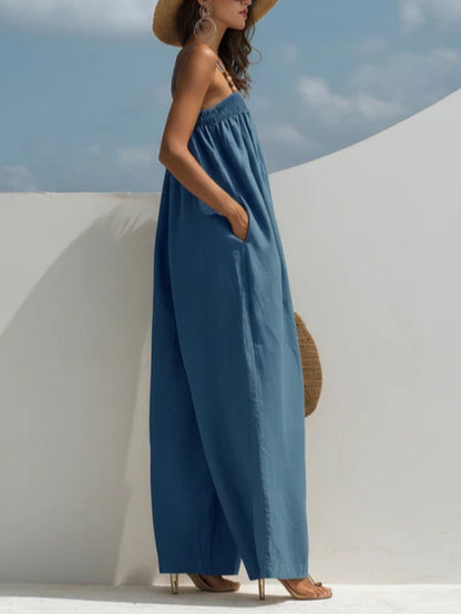 Combinaison en denim bleu ample à bretelles fines et taille élastiquée, jambes larges.