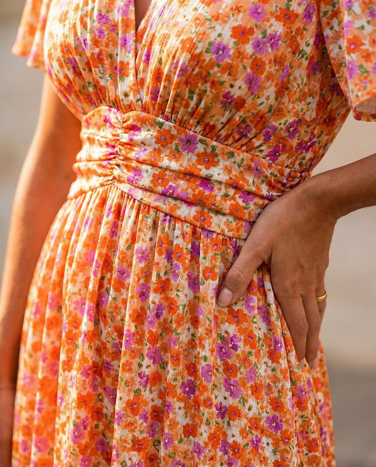 Robe d’été orange à fleurs avec taille froncée et plis sur le buste