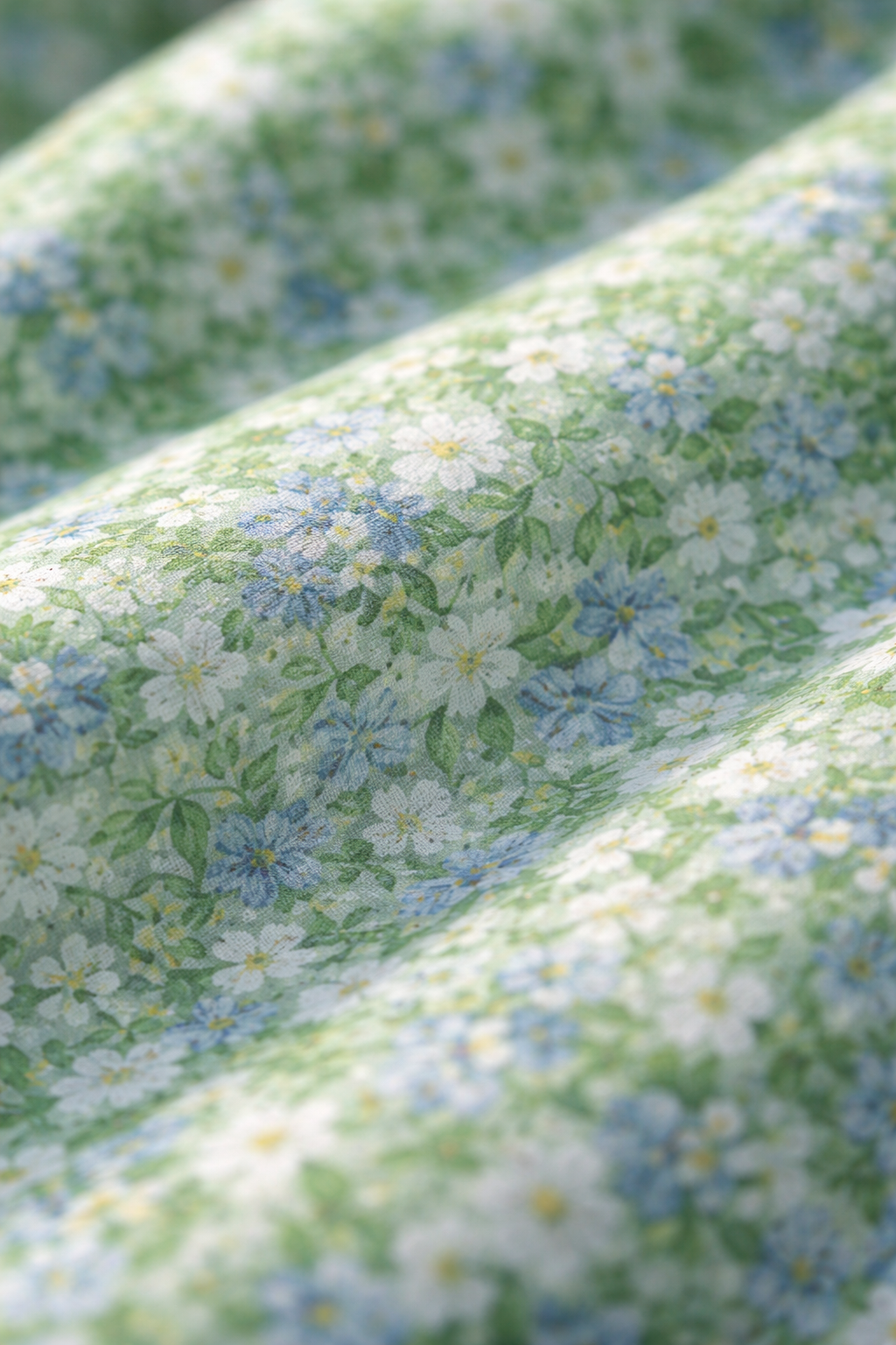 Détail tissu robe d’été verte : motif fleuri sur fond vert pâle