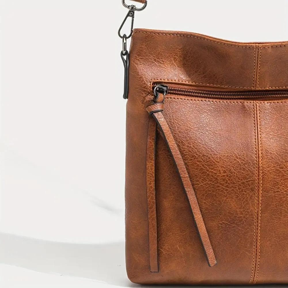 Sac en cuir marron avec grand zip noir et breloque en tissu à franges