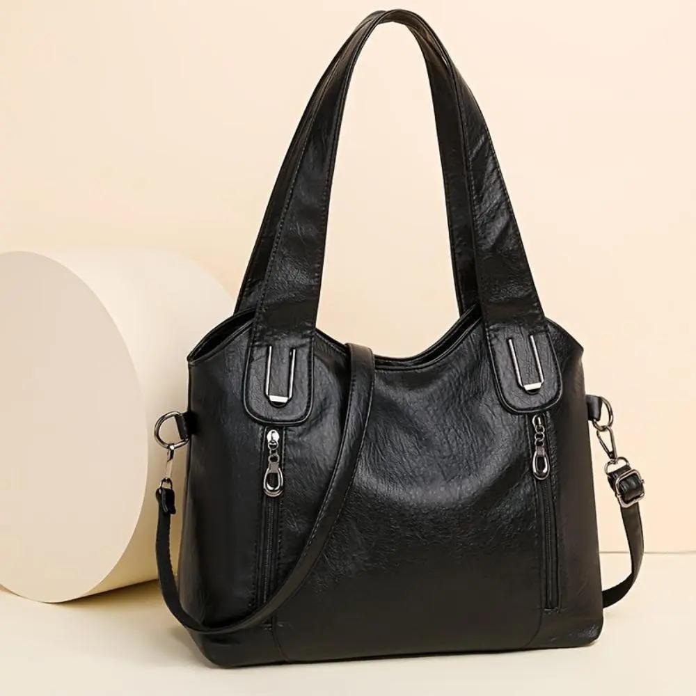 Sac à bandoulière en cuir noir, anses rembourrées et poches zippées