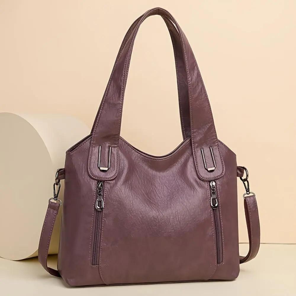 Sac à bandoulière en cuir violet, fermetures zippées et bandoulière réglable