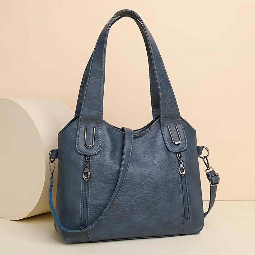 Sac à bandoulière en cuir bleu, anses avec boutons-anneaux et fermeture zippée