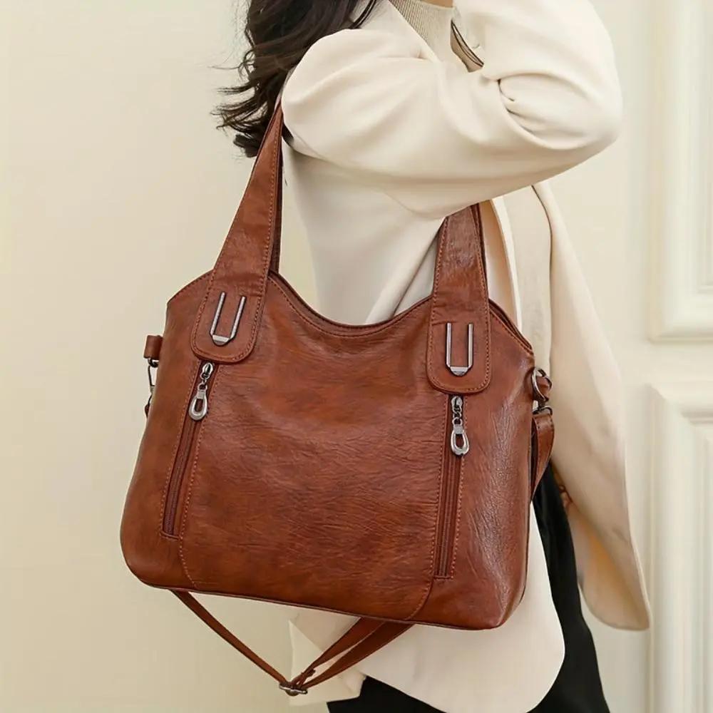Sac à bandoulière en cuir marron sur l’épaule, bandoulière réglable