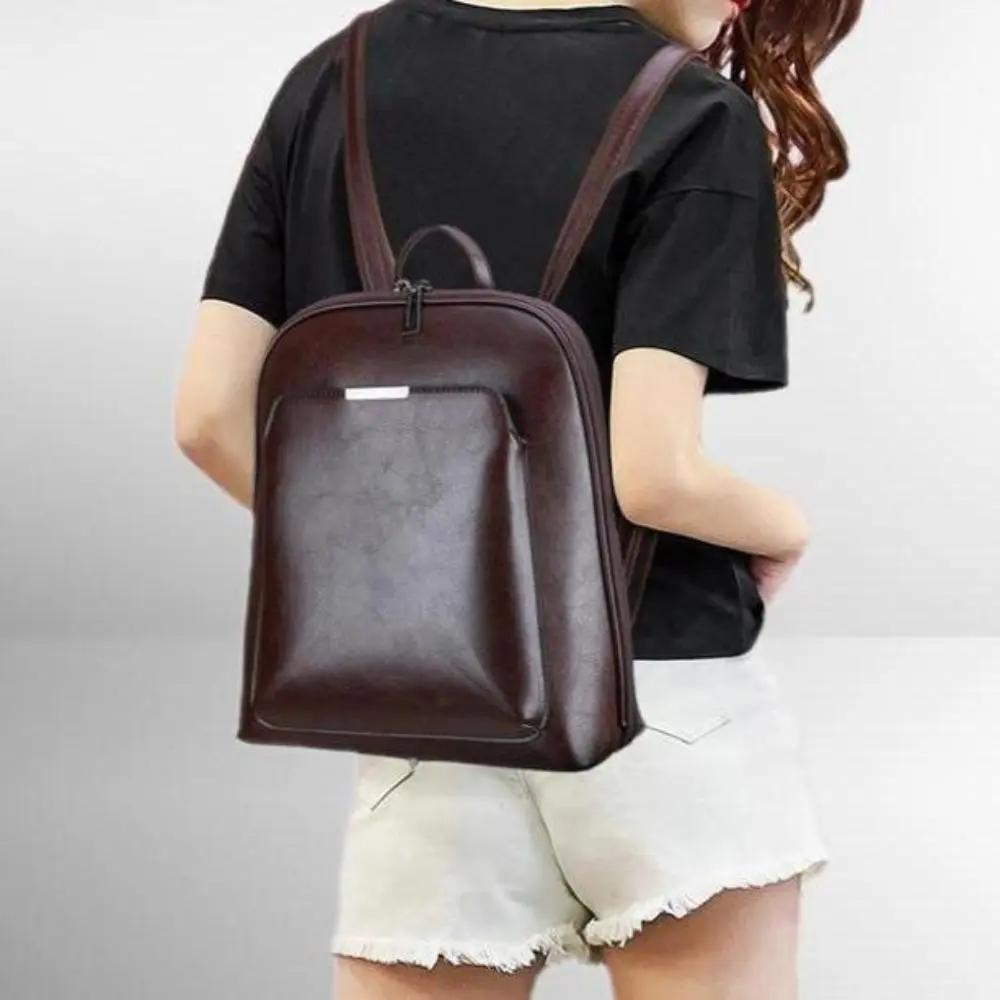 Sac à dos en cuir marron à double fermeture, porté devant avec bretelles