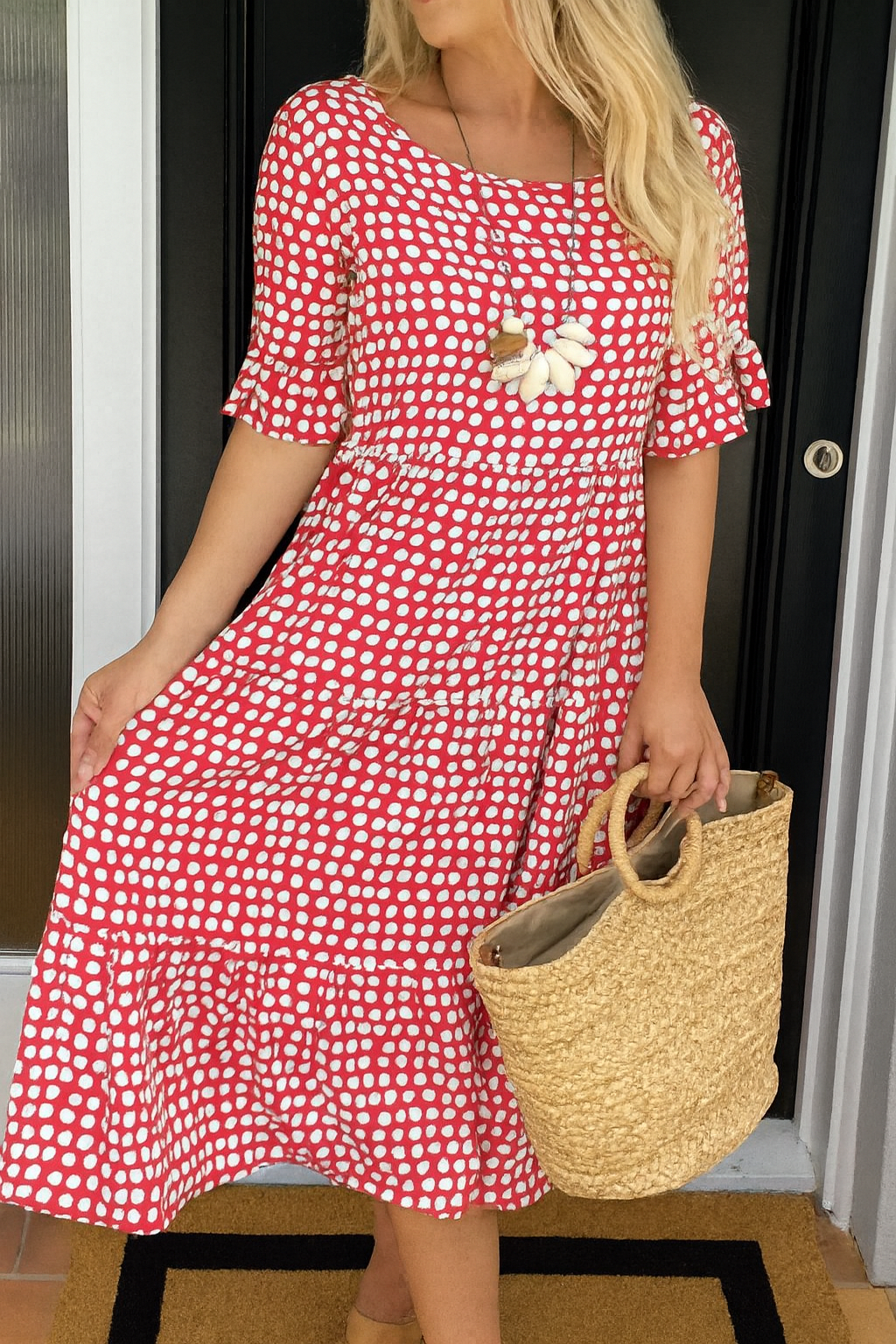 Robe midi fluide rouge à pois blancs, manches courtes, encolure carrée, fleur au buste.