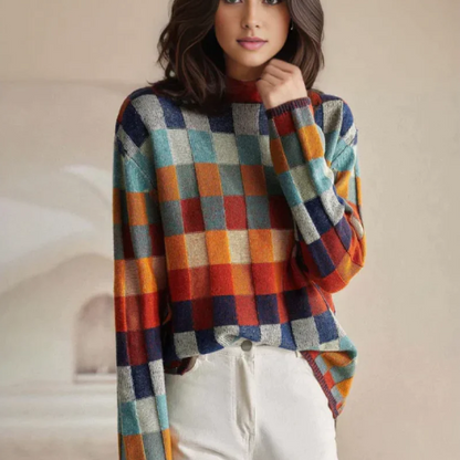Pull en cachemire à col roulé, carreaux orange, bleu, vert et beige, porté avec pantalon clair.