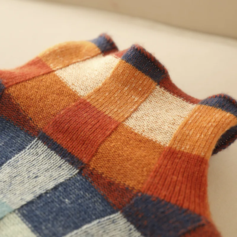 Zoom sur les carreaux du pull en cachemire : orange, terracotta, bleu et beige.