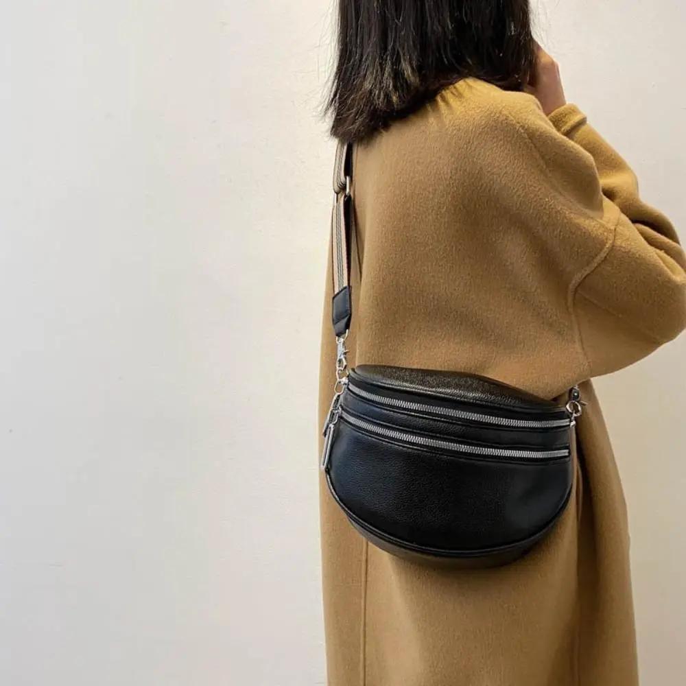 Sac à bandoulière Mira noir, porté en travers, zip sur le devant et sangle rayée.