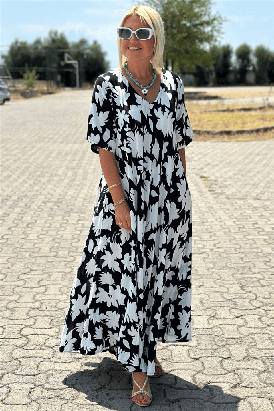 Robe longue ample noire à motifs floraux blancs, manches courtes, encolure en V