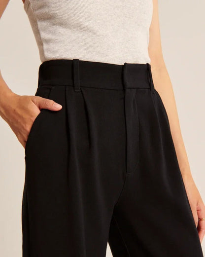 Pantalon noir taille haute avec ceinture à passants, pinces devant et poches.