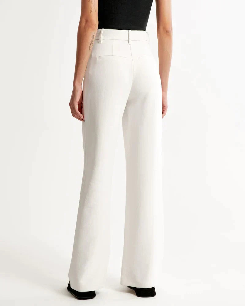 Pantalon blanc taille haute, jambes larges, passants de ceinture et poches.