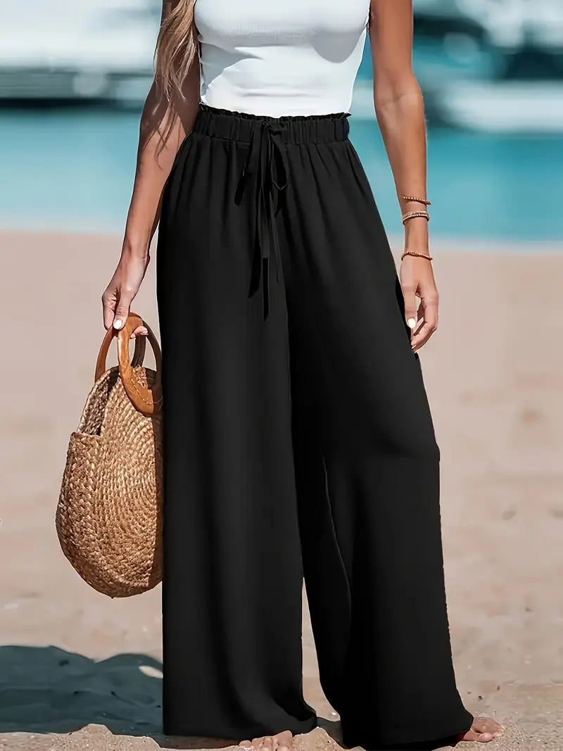 Pantalon taille haute noir fluide, jambe ample, ceinture élastique avec lien devant.