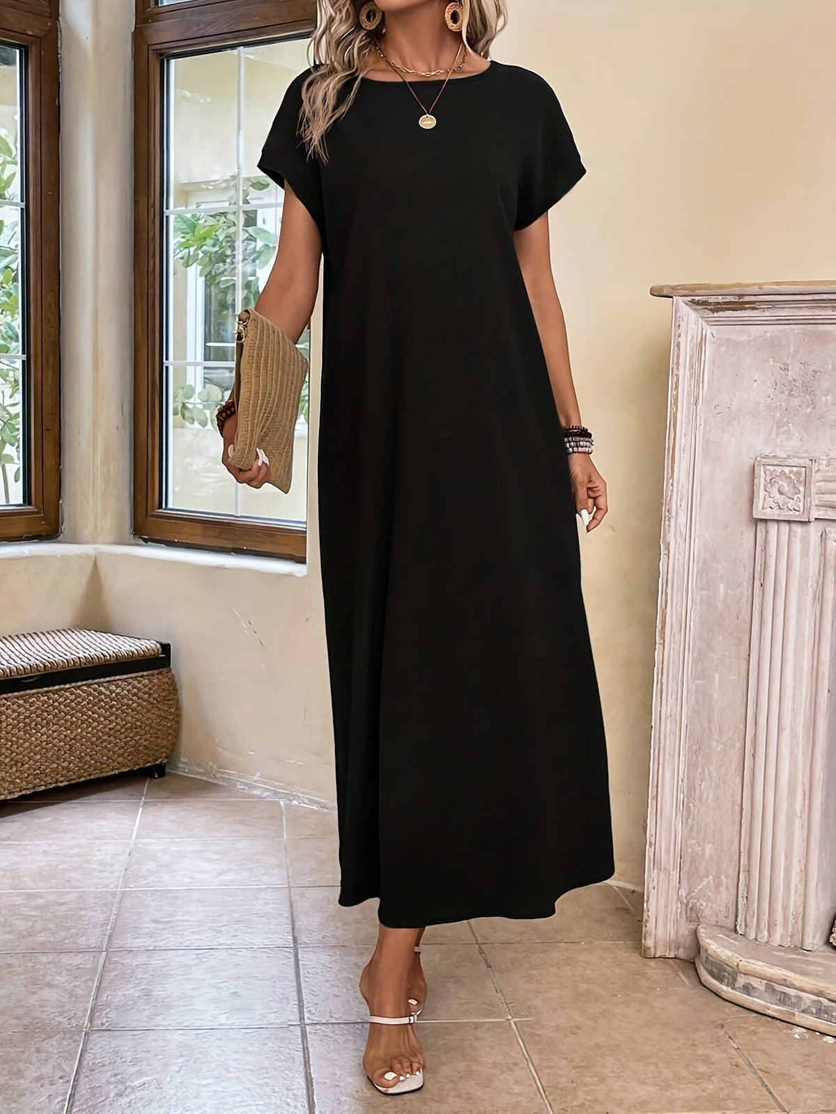 Robe longue noire à manches courtes, encolure ronde et fente légère sur le bas.