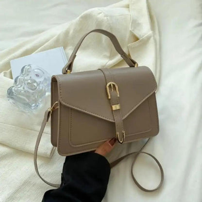 Sac à bandoulière beige avec rabat structuré et fermoir doré, poignée courte et sangle.