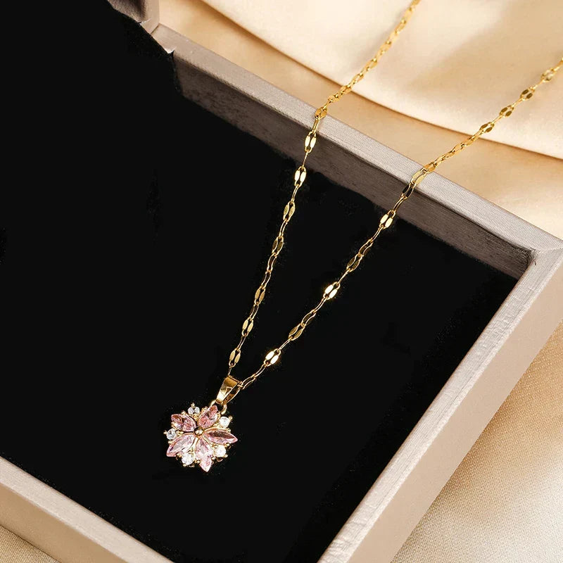 Collier fin doré avec pendentif fleur rose en strass, présenté sur boîte noire