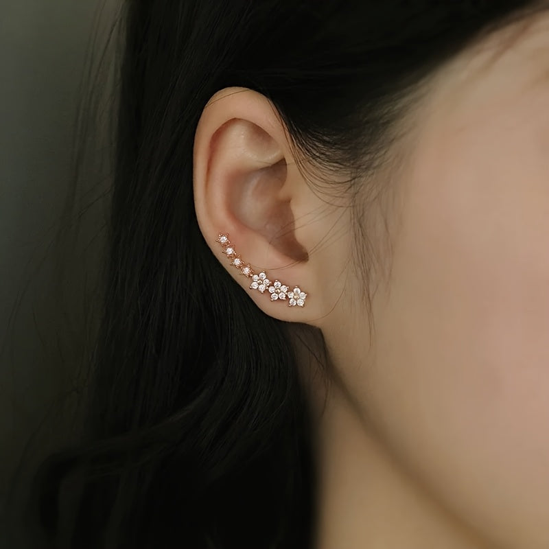 Boucles d’oreilles florales en or rose, motif en rangée de petites fleurs, vue portée
