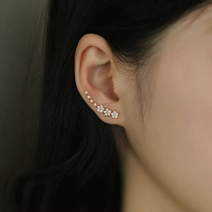 Boucles d’oreilles fleurs en strass rosé, portées, motif floral le long de l’oreille.