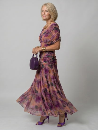 Robe longue en mousseline violette à fleurs, épaules dénudées, manches évasées.