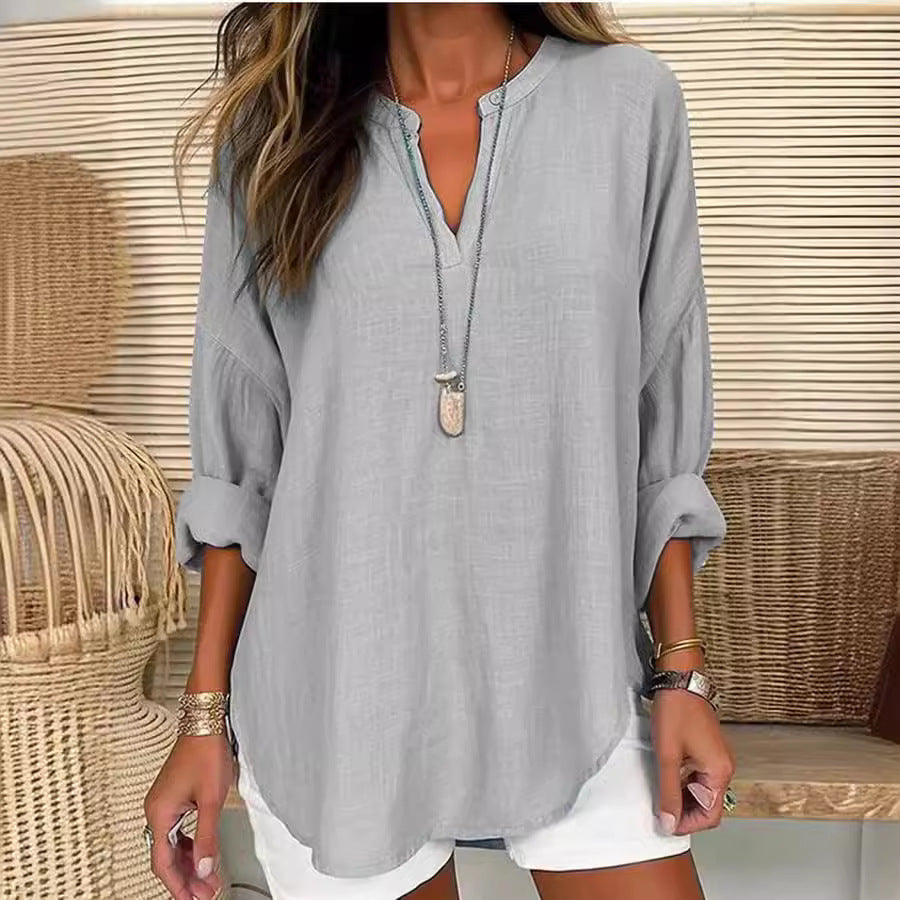 Blouse ample en tissu gris clair, encolure V boutonnée, manches trois-quarts.