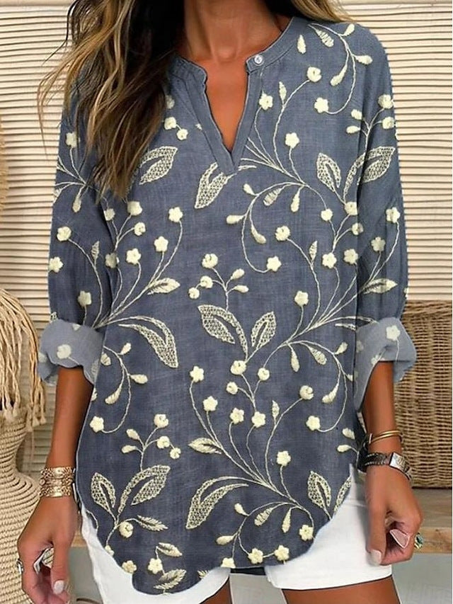 Blouse ample bleu foncé à motifs floraux beiges, encolure V boutonnée.