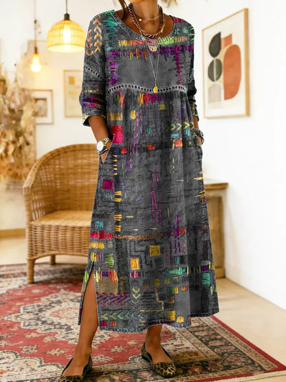 Robe longue imprimée ethnique sur fond sombre, motifs multicolores, encolure ronde, fente.