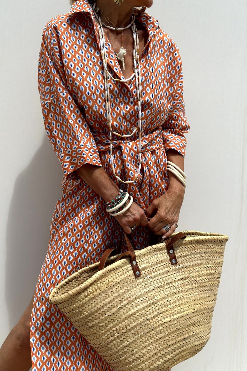 Robe chemise à motifs géométriques orange et blancs, ceinture à nouer, manches boutonnées.