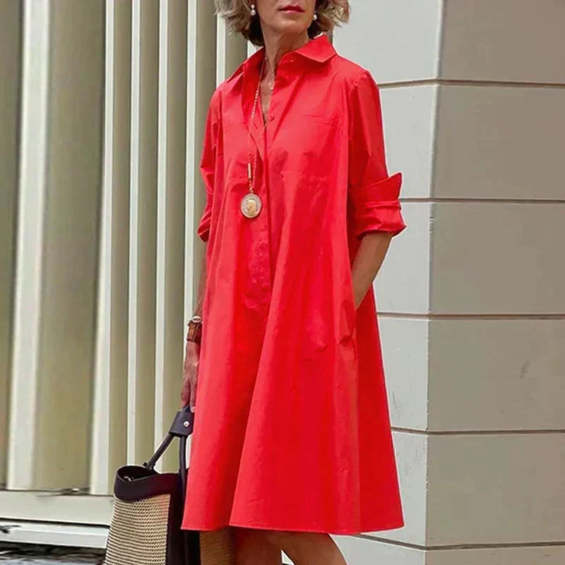 Robe mi-longue rouge à col chemise, boutonnage devant et poignets retroussés.