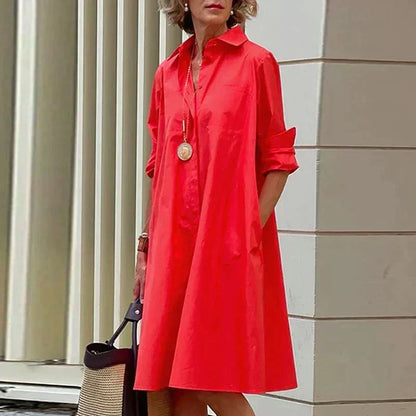 Robe mi-longue rouge à col chemise, boutonnage devant et poignets retroussés.