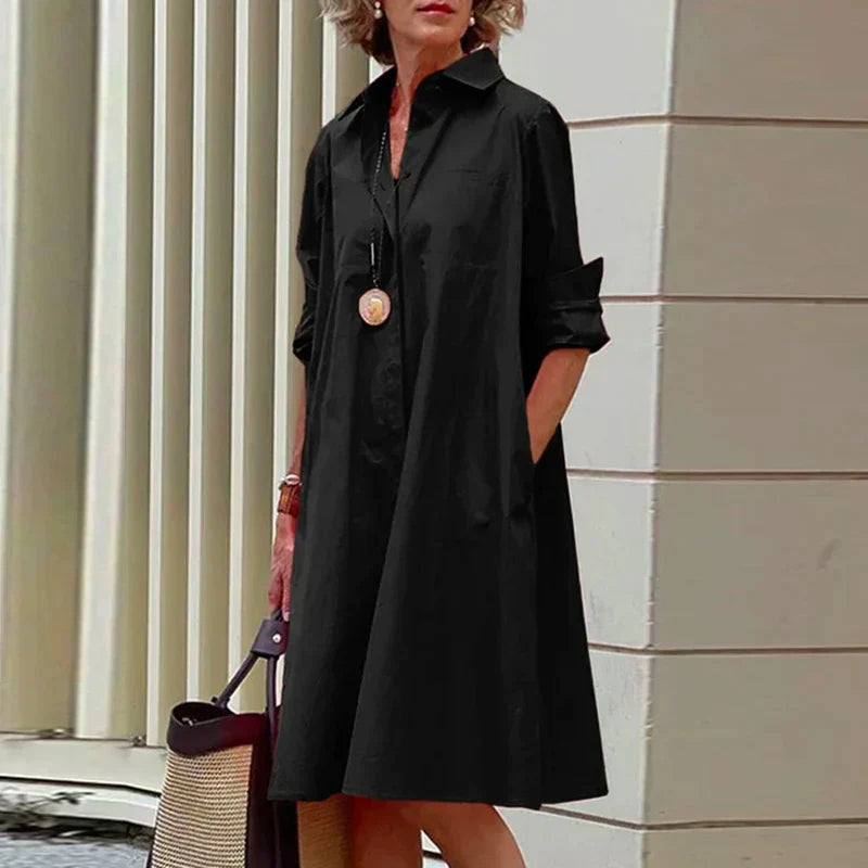 Robe mi-longue noire à col chemise, boutonnage devant et manches retroussées.
