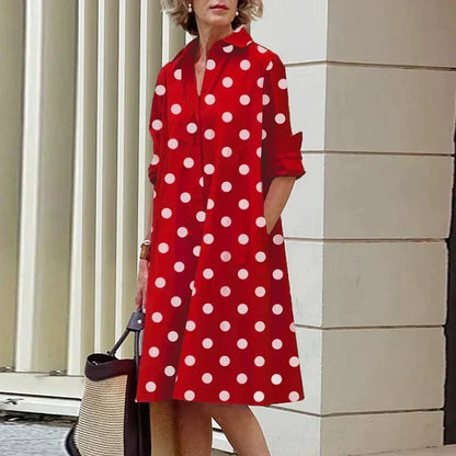 Robe mi-longue rouge à pois blancs, col chemise et boutonnage devant, manches retroussées.
