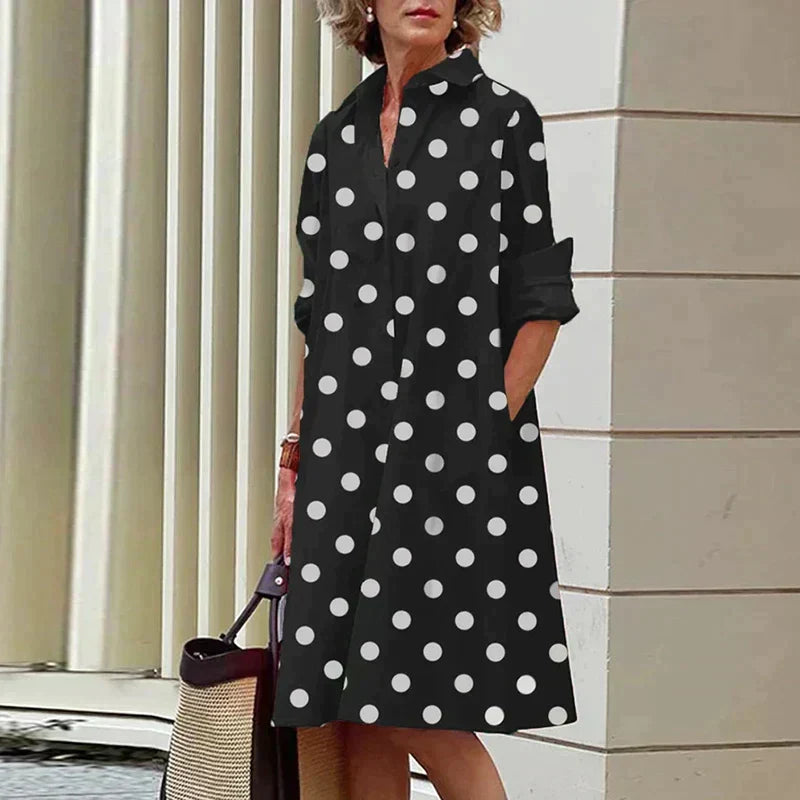 Robe noire mi-longue à pois blancs, col chemise et manches trois-quarts.