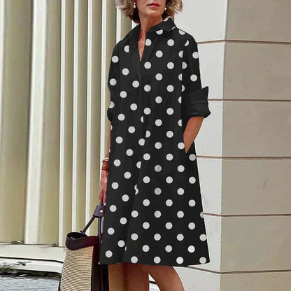 Robe noire mi-longue à pois blancs, col chemise et manches trois-quarts.