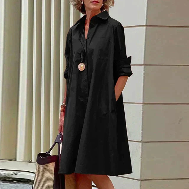 Robe mi-longue noire à col chemise, boutonnage devant et manches retroussées.