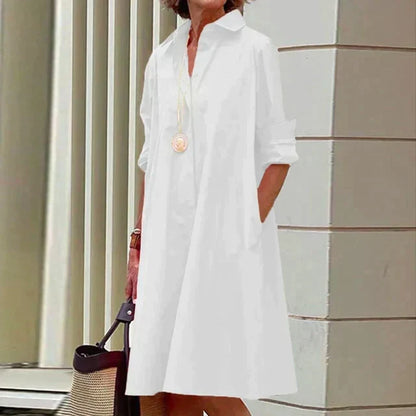 Robe mi-longue blanche à col chemise, boutonnage devant et manches retroussées.