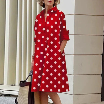 Robe mi-longue rouge à pois blancs, col chemise et boutonnage devant, manches retroussées.
