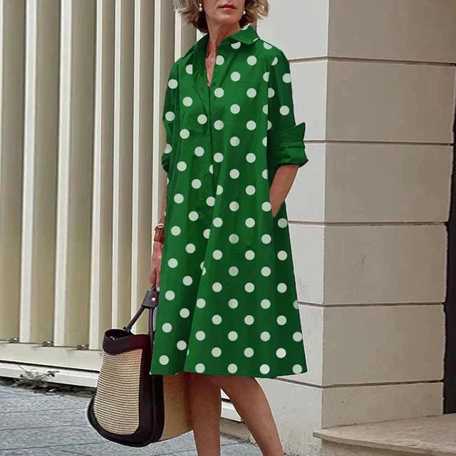 Robe verte mi-longue à pois blancs, col chemise boutonné, manches trois-quarts.