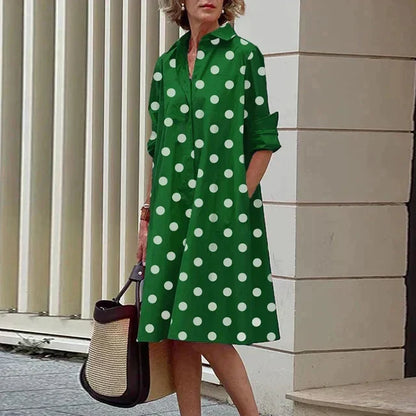 Robe verte mi-longue à pois blancs, col chemise boutonné, manches trois-quarts.