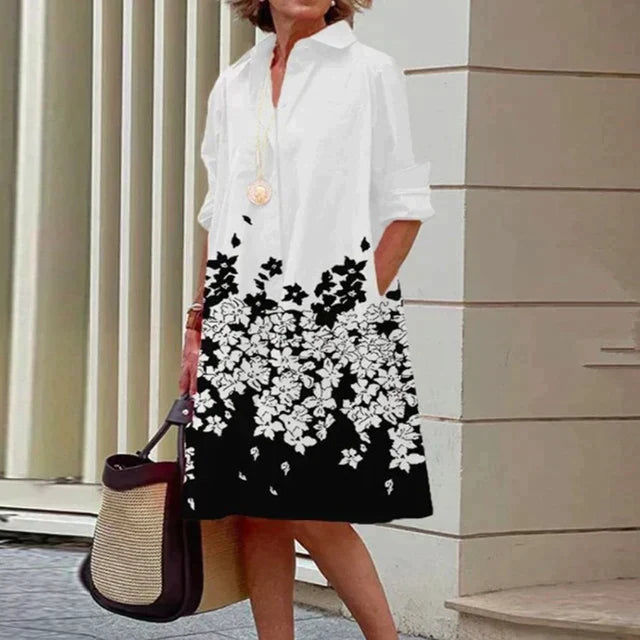 Robe mi-longue blanche à fleurs noires, col chemise, manches trois-quarts.