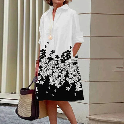 Robe mi-longue blanche à fleurs noires, col chemise, manches trois-quarts.