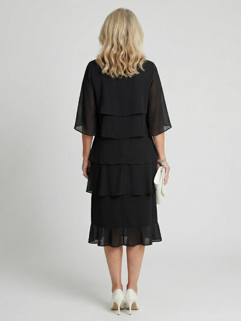 Robe midi noire étagée vue de dos, volants superposés, manches trois-quarts évasées