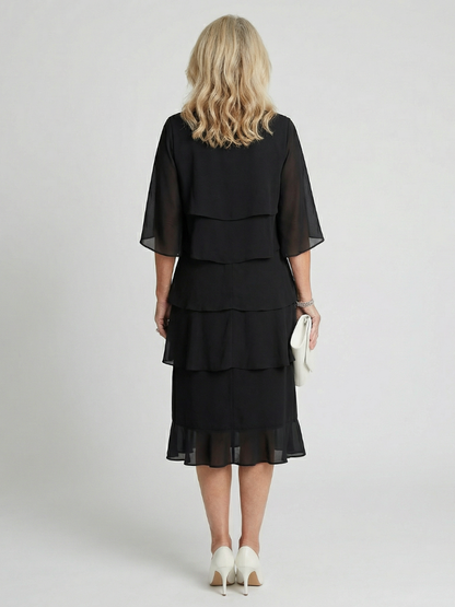 Robe midi noire étagée vue de dos, volants superposés, manches trois-quarts évasées