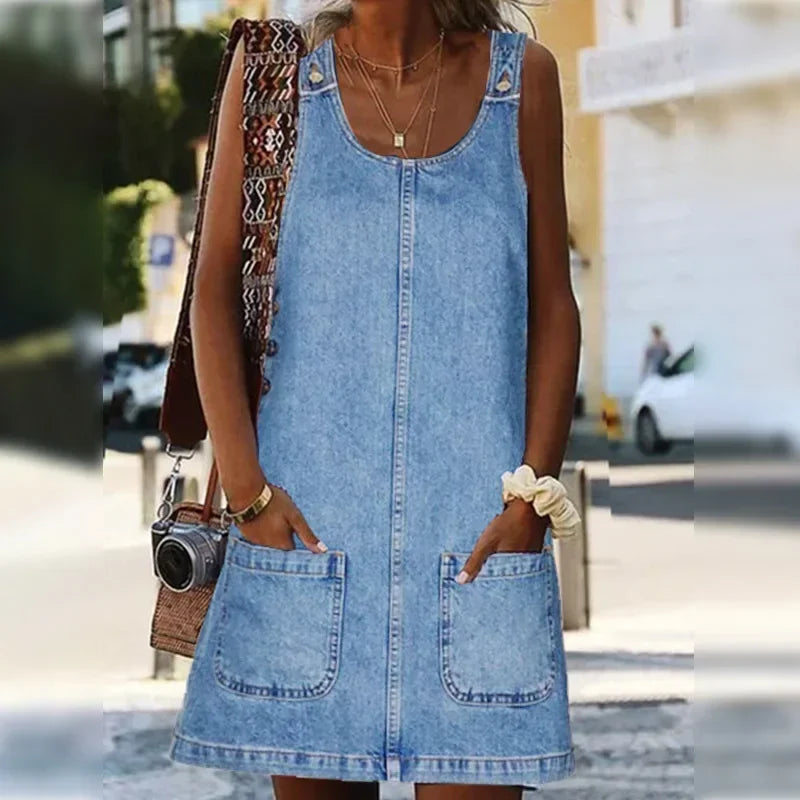 Robe en jean bleu clair sans manches, vue de côté, deux poches plaquées au bas.