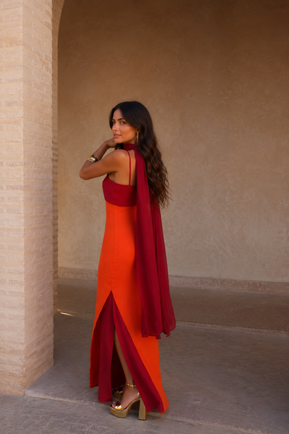 Robe longue orange avec fente, bretelles fines, nœud bordeaux et voile au dos.