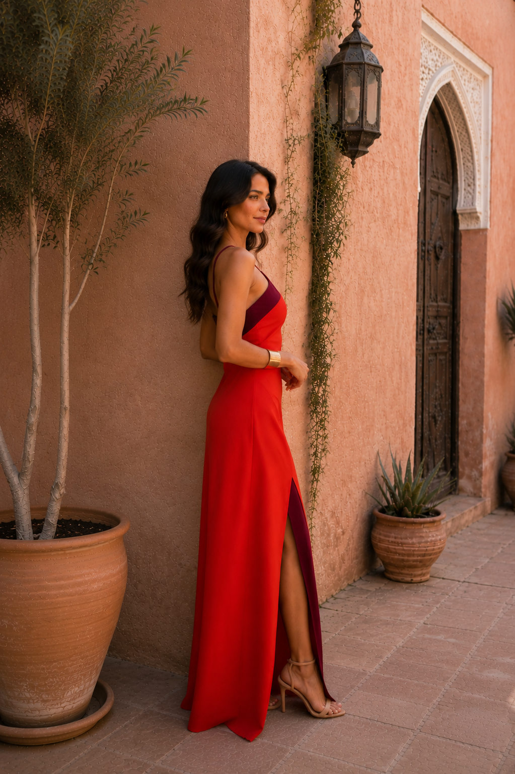 Robe longue rouge, bretelles fines, buste bordeaux et fente sur le côté.