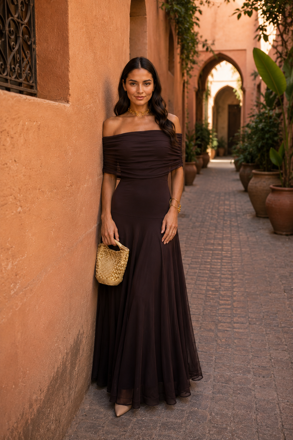 Robe marron foncé hors épaule asymétrique, buste drapé, jupe longue et légère.