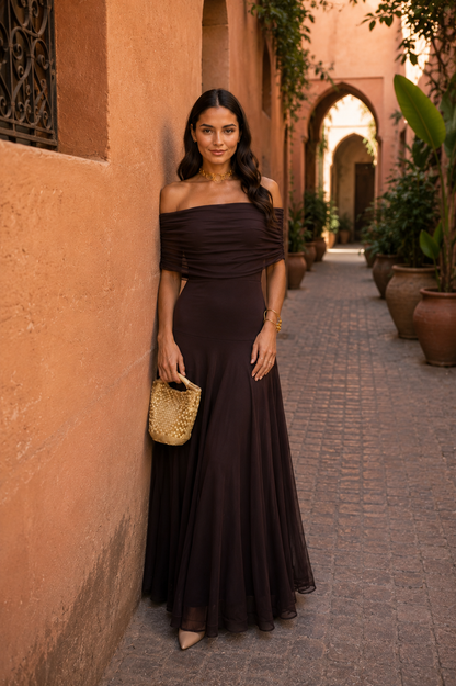 Robe marron foncé hors épaule asymétrique, buste drapé, jupe longue et légère.