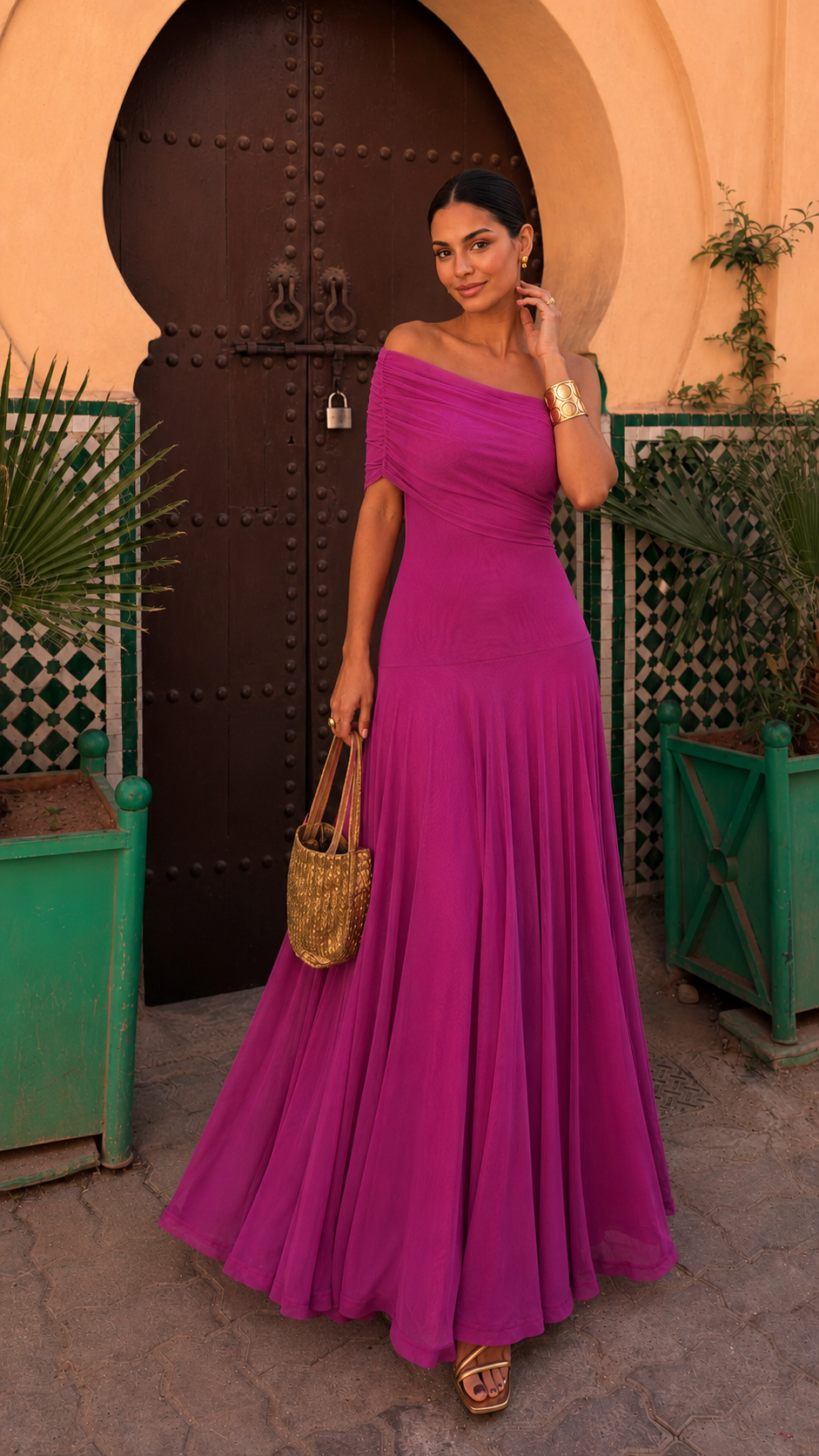 Robe longue fuchsia à une épaule, jupe plissée, sac panier et bracelets dorés